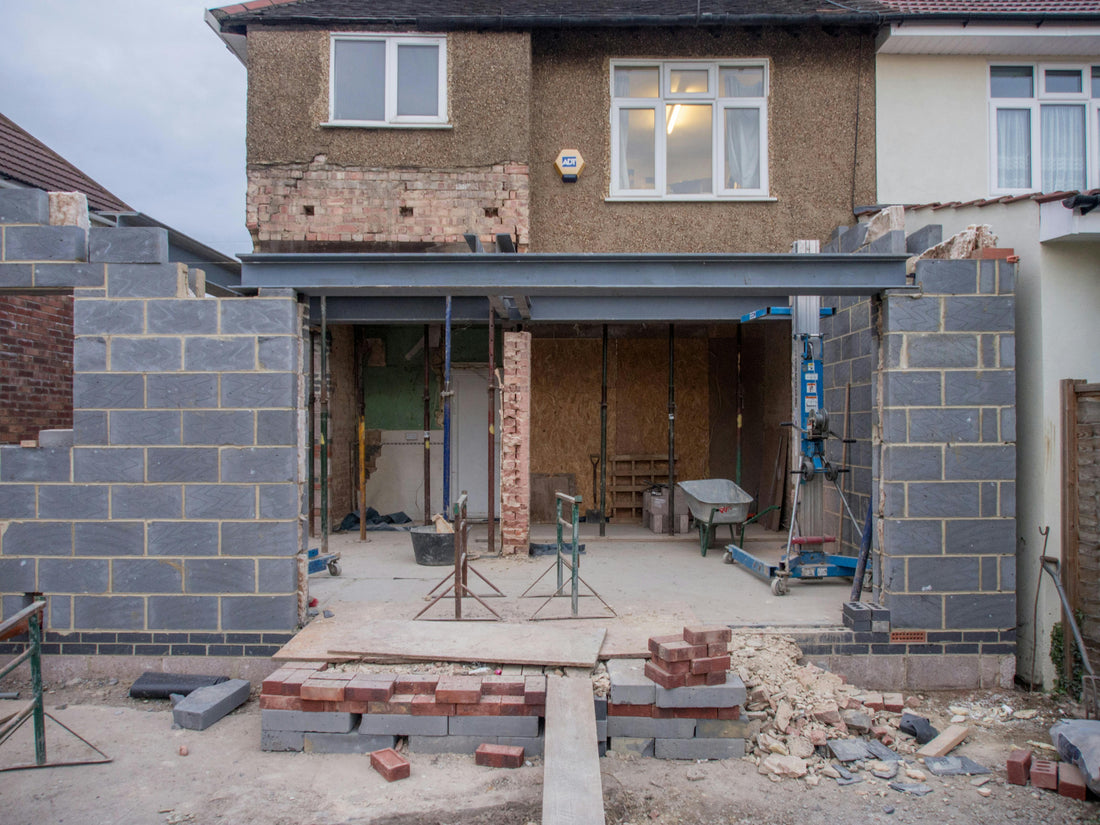 UK home renovation project showing kitchen extension construction with concrete base, brickwork, and building materials in progress