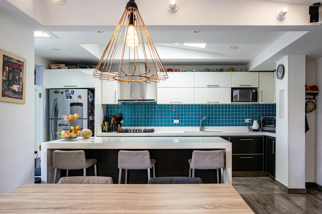 Modern UK kitchen extension with white cabinets, blue tile backsplash, island seating, and warm pendant lighting