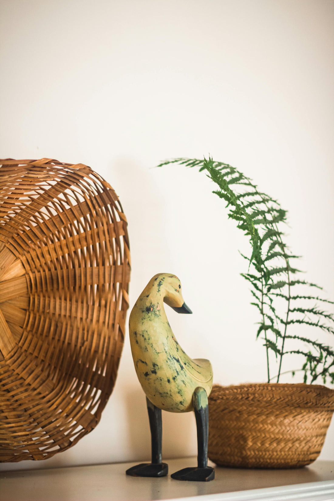 Neutral jungle nursery decor featuring woven natural textures, a rustic wooden bird figure, and earthy botanical styling for a calm and cozy baby room aesthetic.